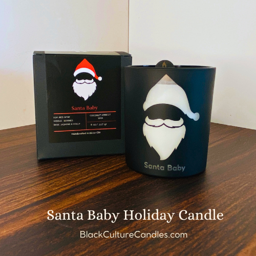 Santa Baby Candle by Black Culture Candles® — a festive luxury Christmas candle in etched matte black glass with a soft holiday glow. Hand-poured with a shimmering vegan coconut-apricot wax blend and a sustainably sourced crackling wood wick, this joyful scent blends strawberry wine, dark plum, jasmine, orange flower, holly berry, vanilla, and musk for a warm, playful fragrance that captures the sparkle of the season