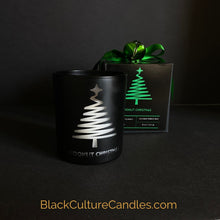 Load image into Gallery viewer, Moonlit Christmas is a limited edition candle in a matte black jar with a modern pine tree engraving. The candle is partially burned, revealing a warm and inviting glow, casting a cozy atmosphere. The label on the jar prominently displays the Black Culture Candles logo. BlackCultureCandles.com
