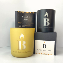 Load image into Gallery viewer, Black Joy luxury scented candle in etched glass with notes of citrus, pineapple, and amber—handcrafted with non-toxic wax and a crackling wood wick. A vibrant scent inspired by Black cultural joy, sunshine, and connection.
